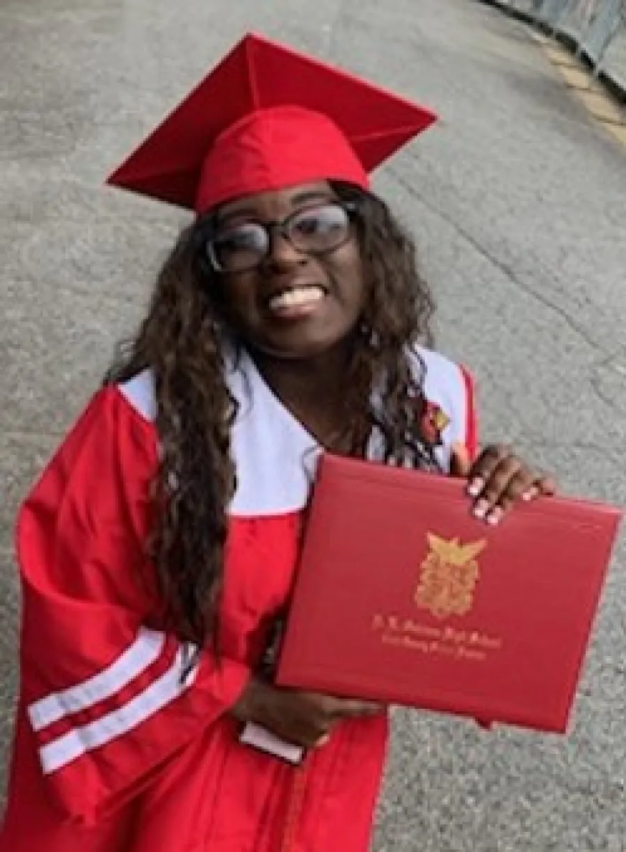 a person wearing a graduation cap and gown holding a red book