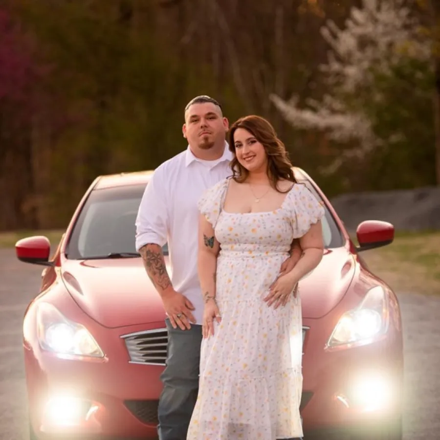 a man and woman posing in front of a car