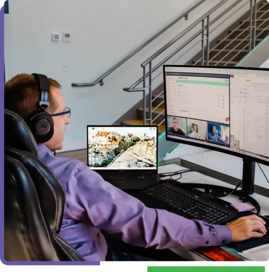 a man wearing headphones and sitting at a desk with a computer