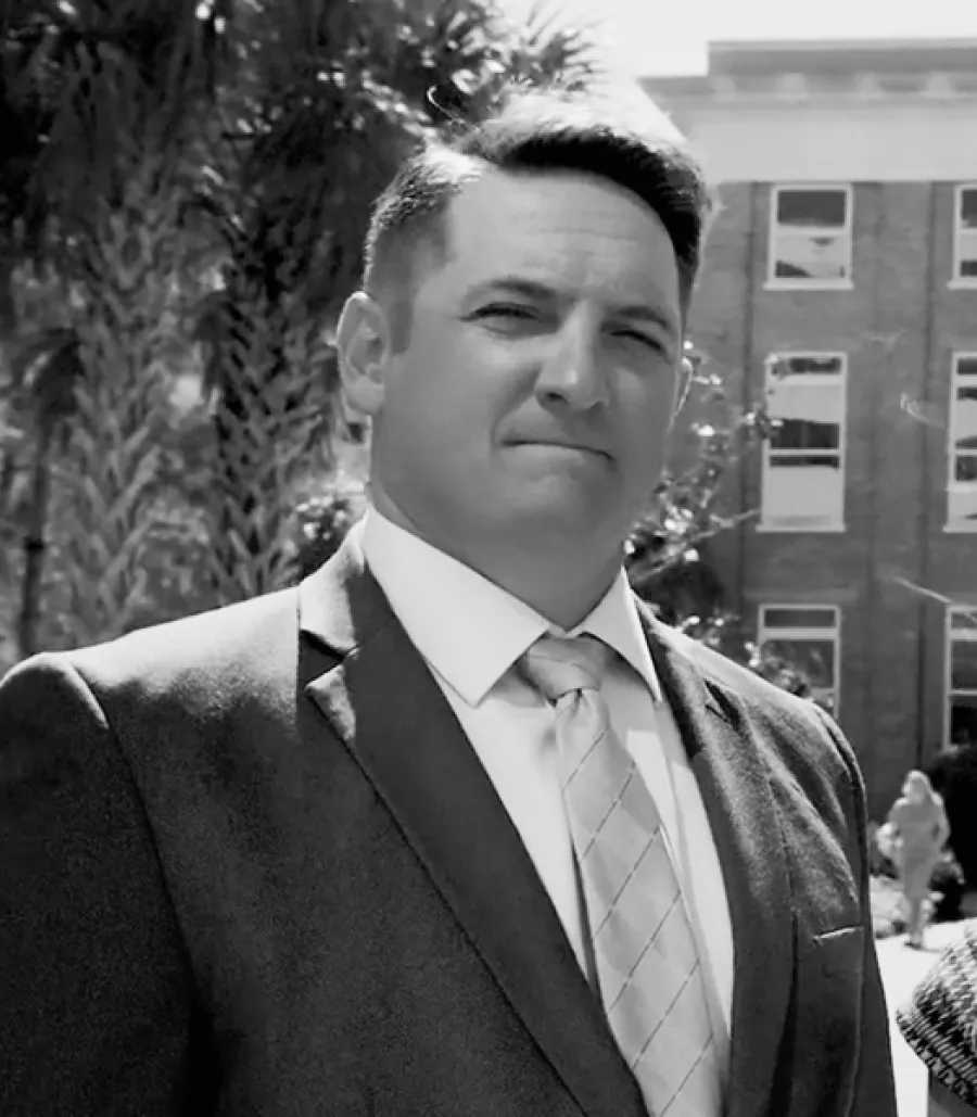 Confident man in a suit and tie standing outdoors near a building on a sunny day