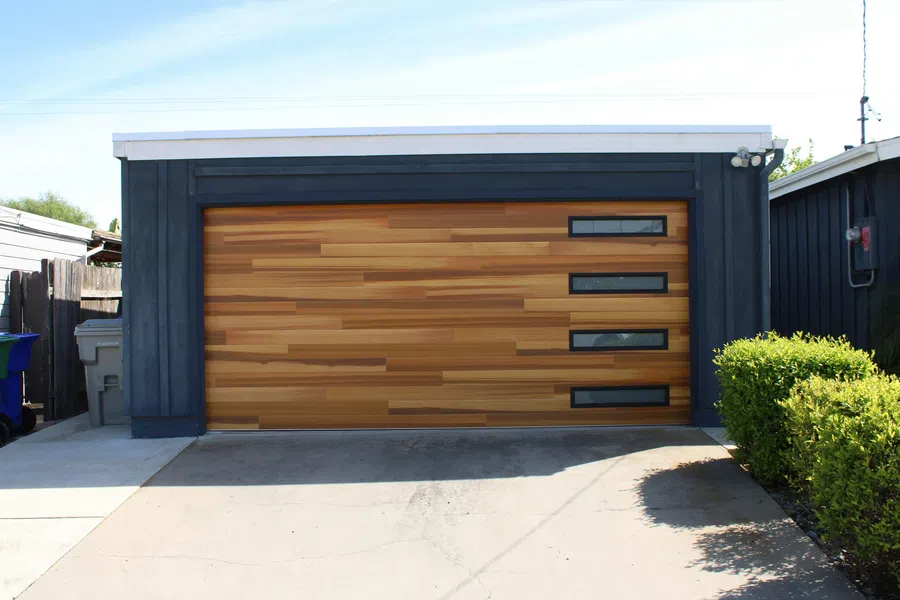 Modern garage with horizontal wooden panel door and four small rectangular windows on the right side.