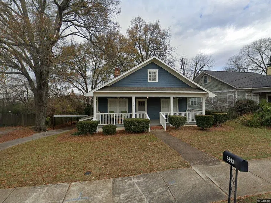 Blue single-story house with white trim, front porch, bushes, and mailbox on a fall day