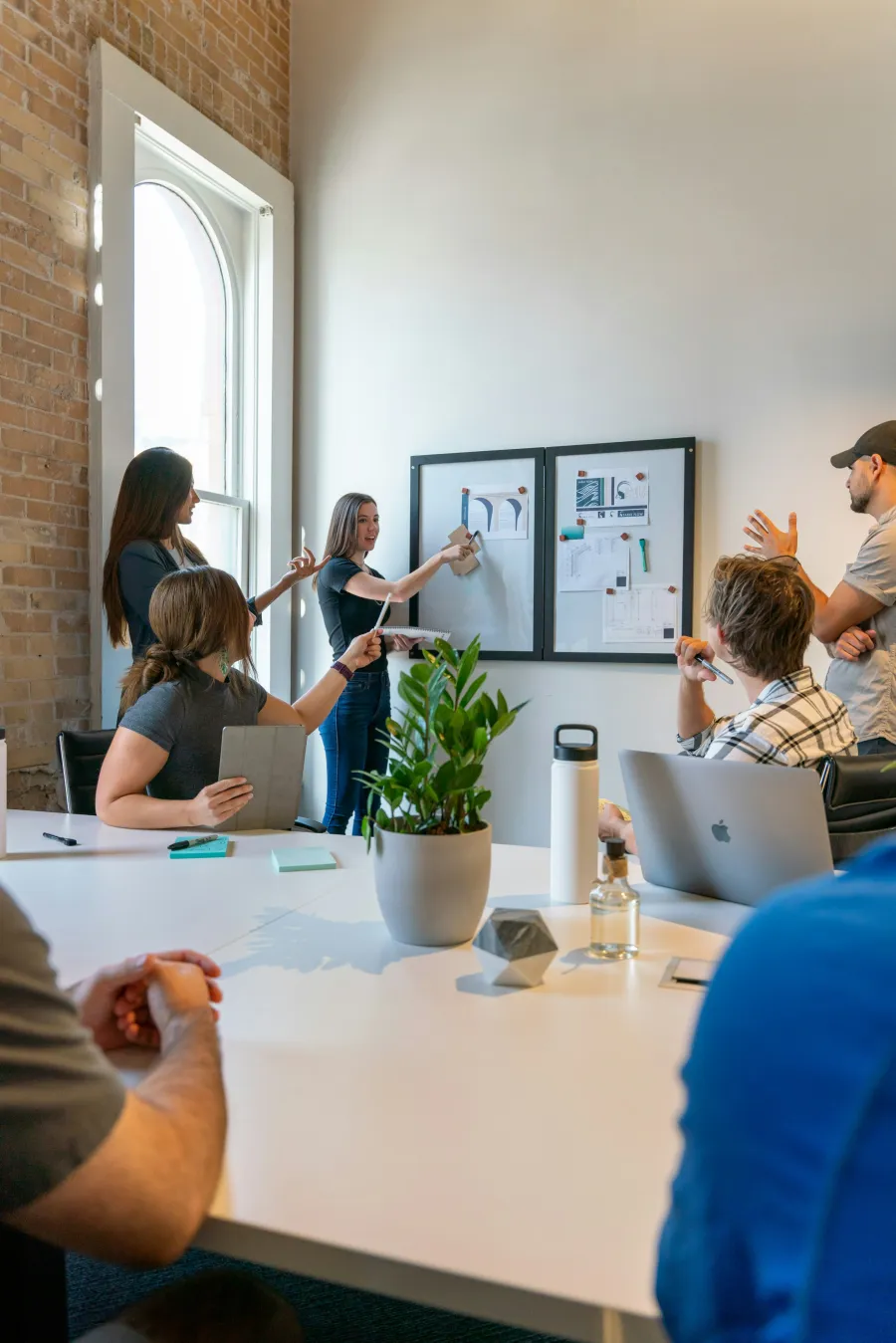 Team collaborating and brainstorming with design sketches on wall in modern office meeting room.