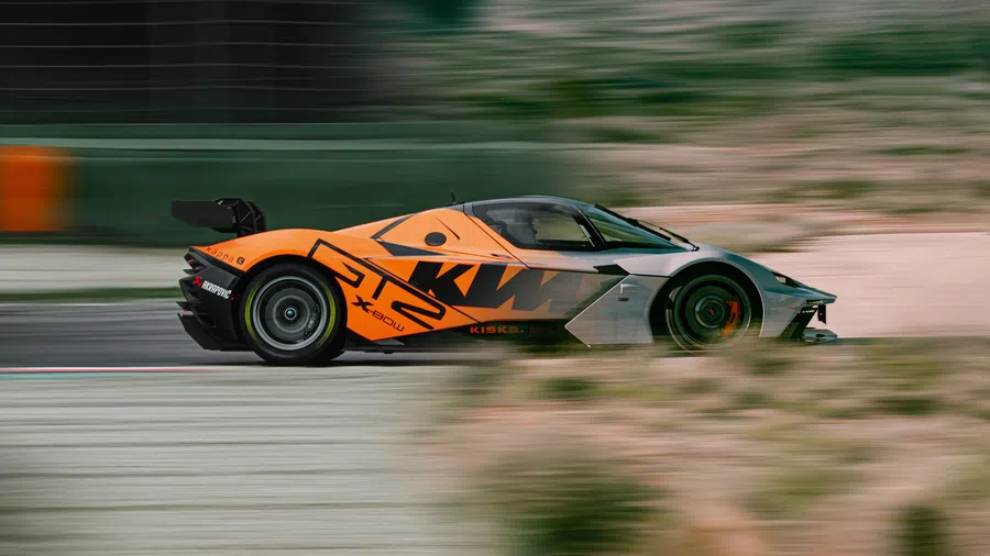 Orange and black KTM X-Bow GT2 race car speeding on a race track with blurred background.