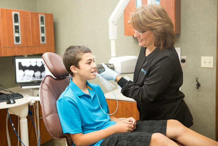 Dentist fitting a young boy with a dental mouthpiece in a modern dental office with x-ray monitor