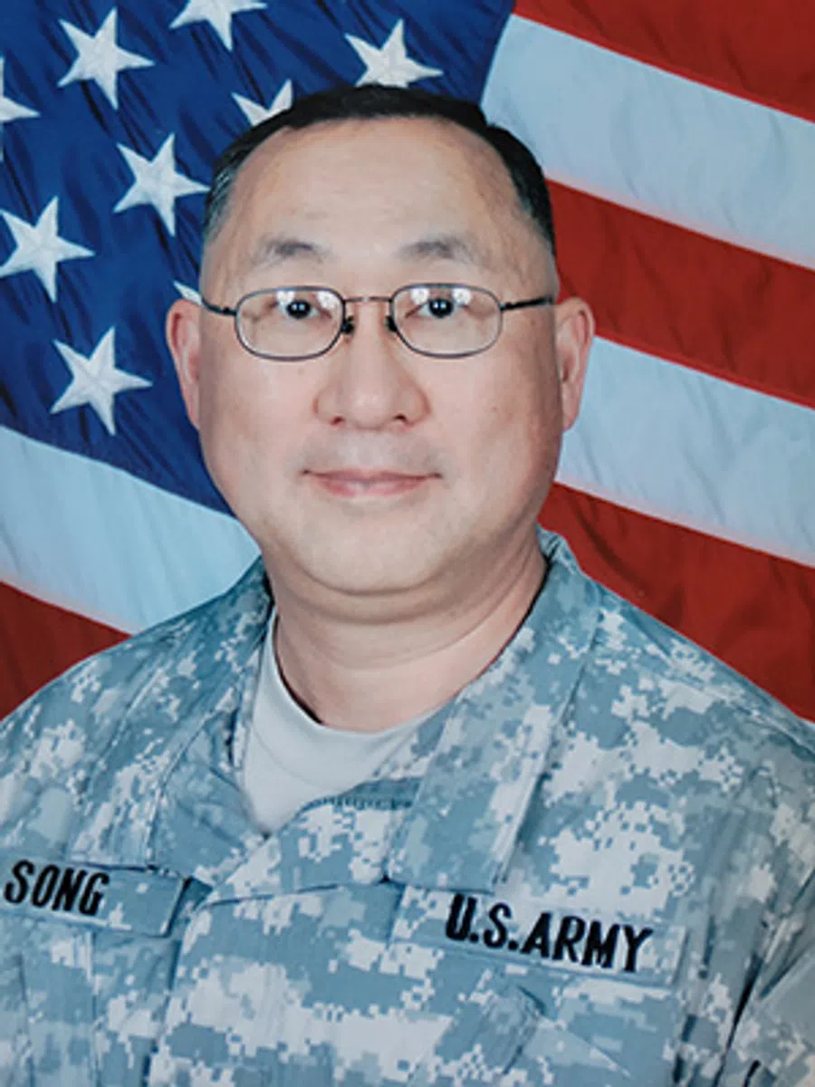 Portrait of a U.S. Army soldier wearing digital camouflage uniform with American flag backdrop.