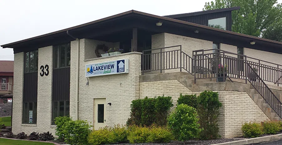 Two-story brick building with Lakeview Assisted Care sign and landscaped greenery outside under cloudy sky