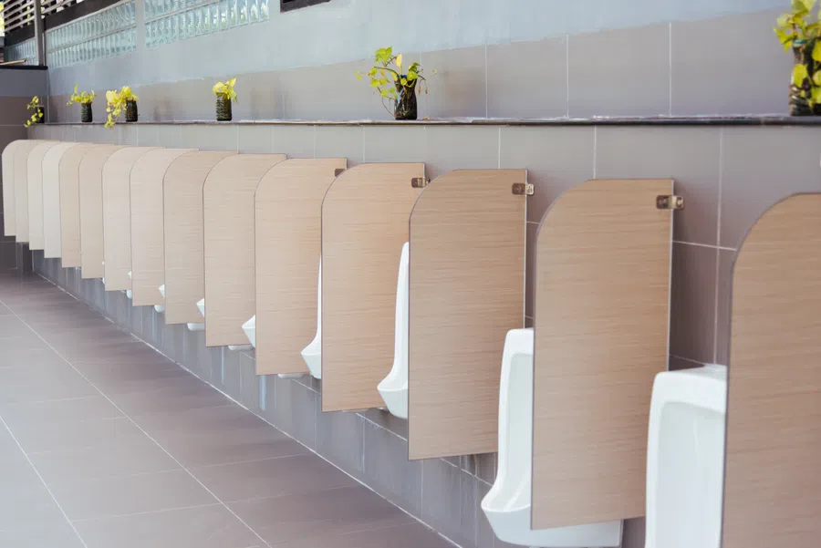 Row of white urinals with wooden privacy partitions in a clean, modern public restroom.