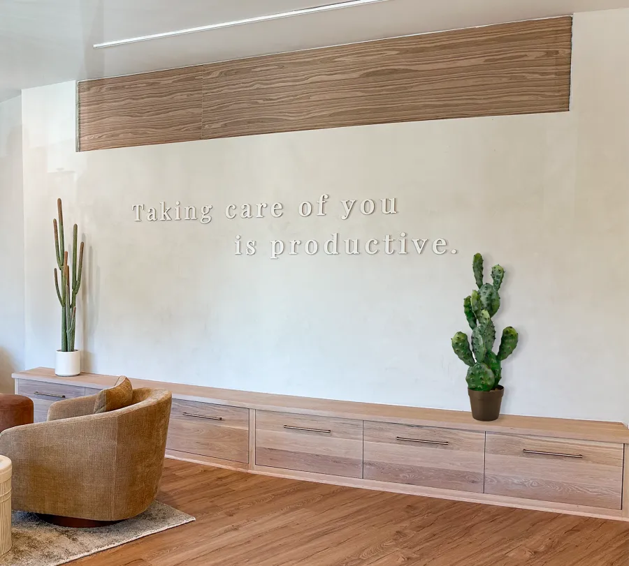 Modern cozy lounge with wooden furniture, a motivational quote on the wall, and potted cactus plants