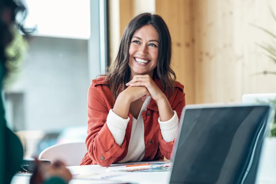 a woman smiling and pointing at a laptop