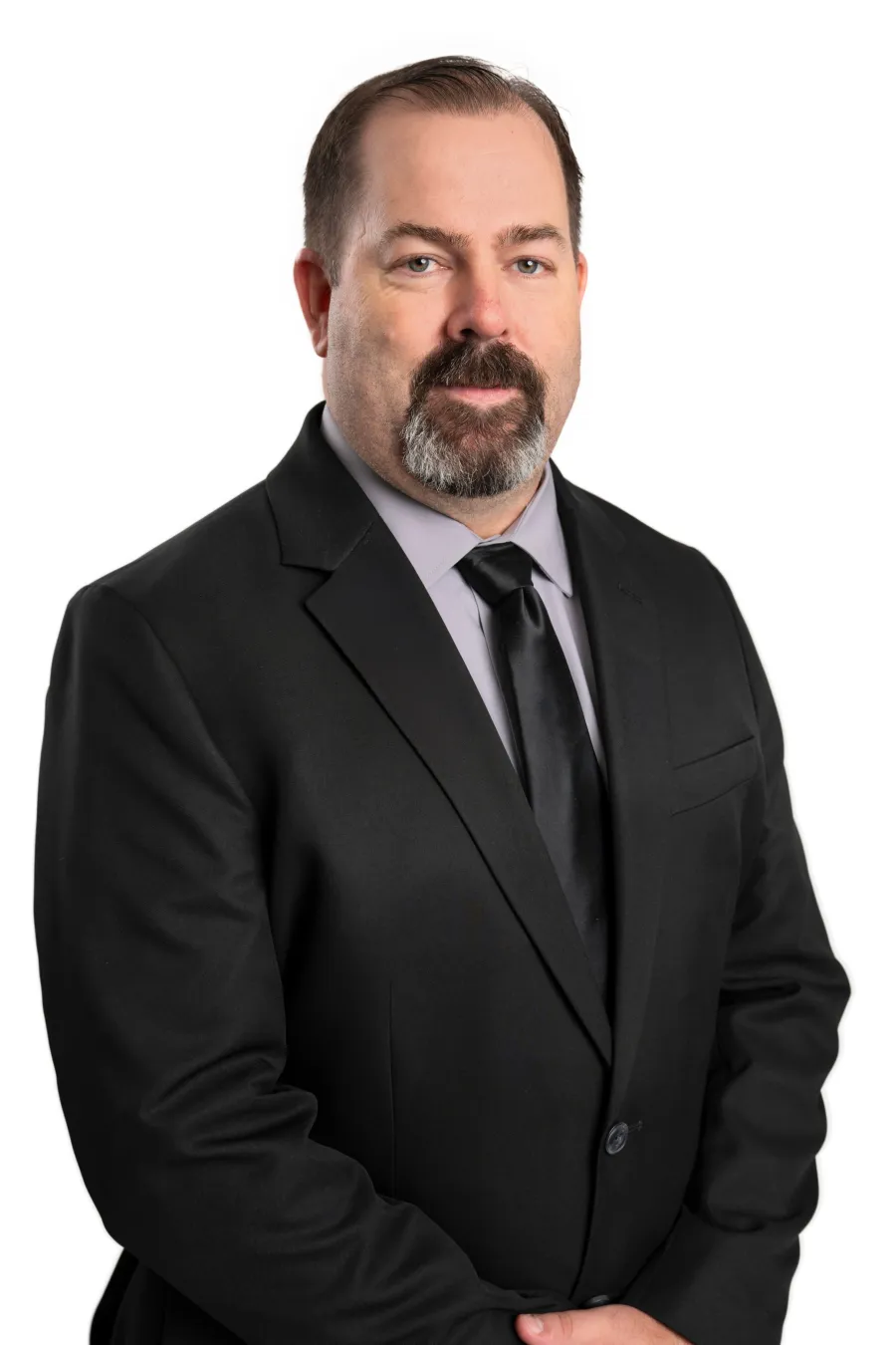 Professional middle-aged man with a beard wearing a black suit and tie against a white background