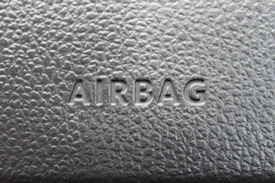 Close-up of textured black car dashboard with embossed AIRBAG safety label.