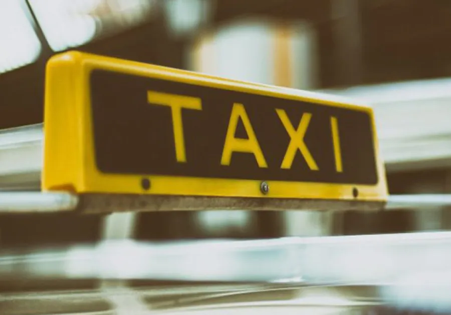Close-up of a yellow taxi sign mounted on a vehicle with blurred background