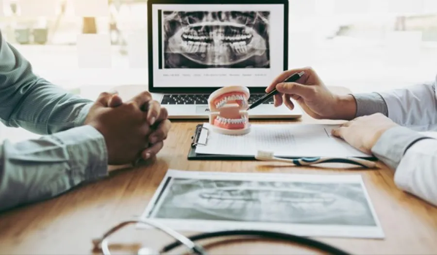 Dentist explaining dental x-rays using a teeth model and digital images during a patient consultation