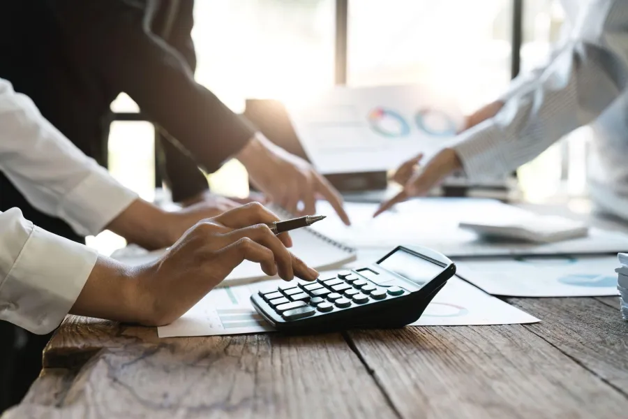 People using a calculator and discussing financial charts in a bright office setting