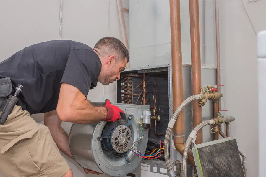 Technician repairing an HVAC unit, focused on motor replacement with tools and equipment nearby.