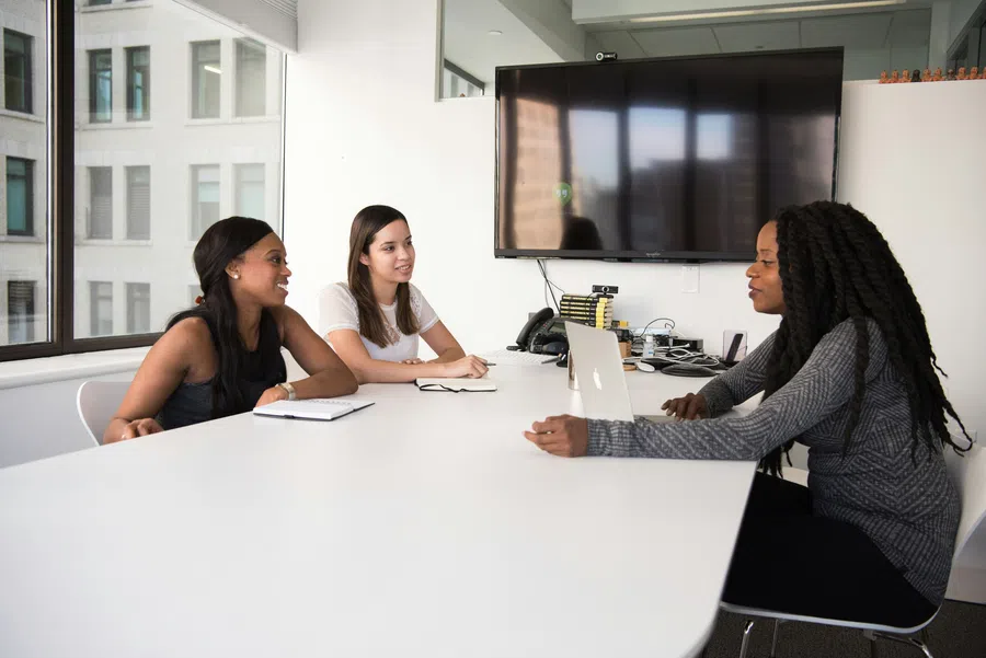 Three women having a business meeting in a modern office with laptops and notebooks on the table