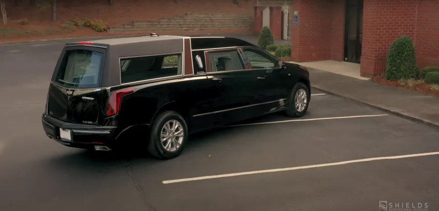 A black hearse parked outside a building, showcasing its elegant design and spacious rear.