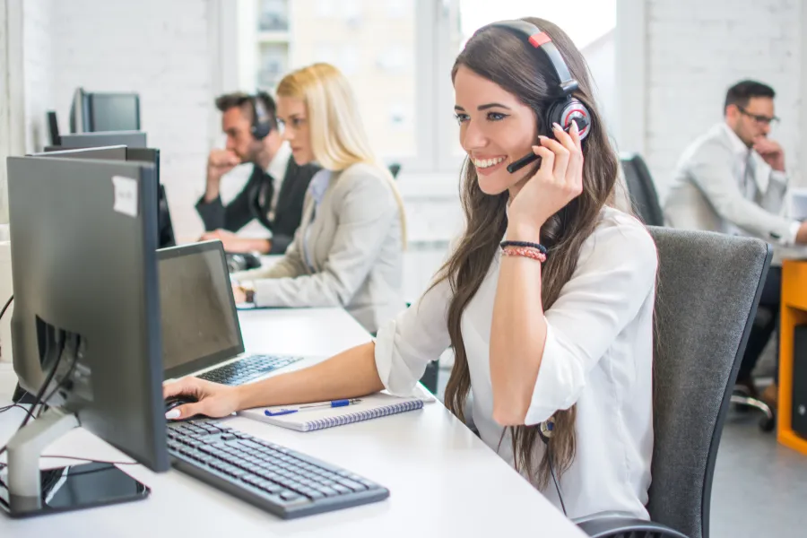 a woman wearing headphones and sitting at a desk with a laptop