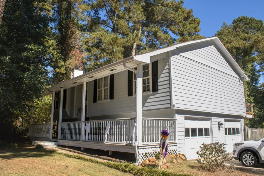 Close-up of a beige house exterior with dormer windows and gray shingles on a sunny day.