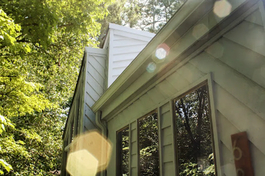 Outdoor staircase with white railings and black balusters leading up to a wooden deck on a sunny day.