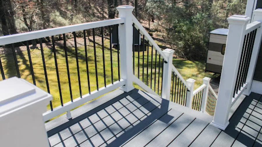Two-story white house with gray roof, double garage, wooden shutters, and green lawn surrounded by trees.