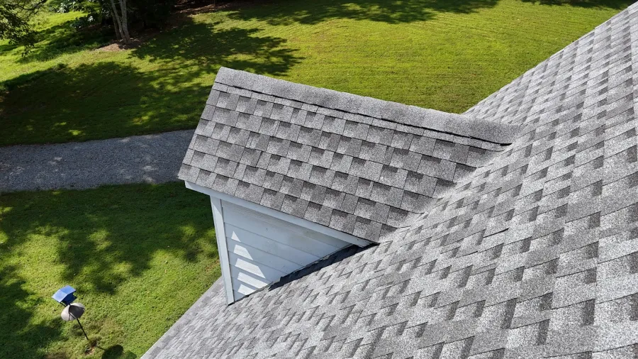 Close-up of a beige house exterior with dormer windows and gray shingles on a sunny day.