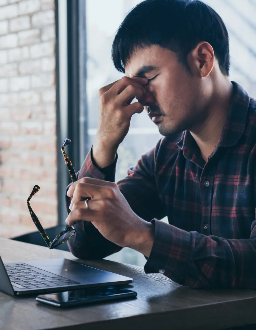 a man sitting at a table with a laptop and a pen