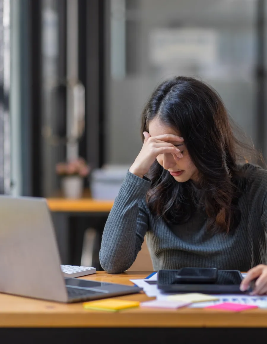 a woman sitting at a desk with her hand on her face