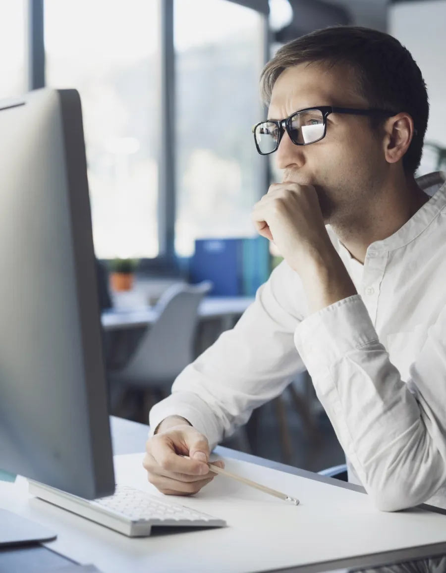 a man sitting at a desk with his hand on his chin