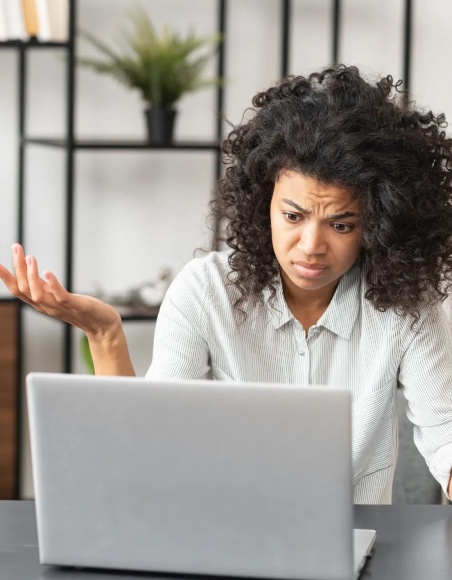 a woman with curly hair sitting at a table with a laptop