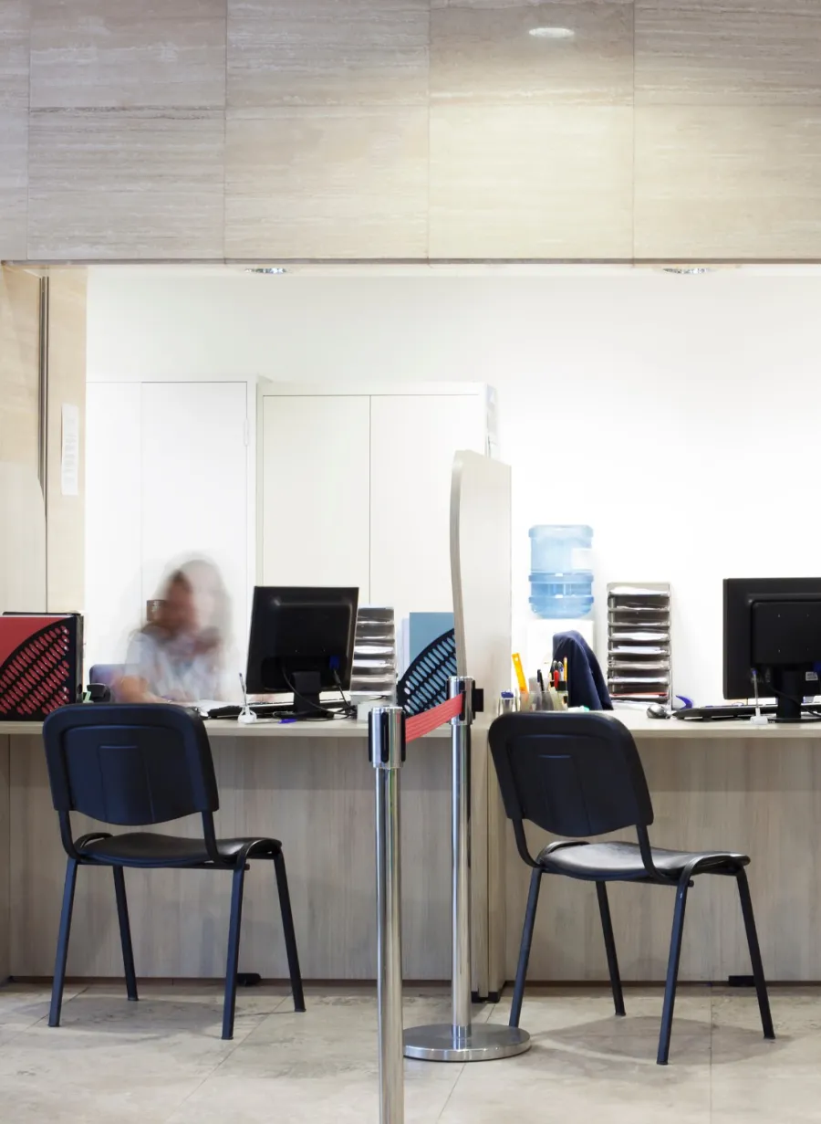 a person sitting at a desk with a computer and several chairs