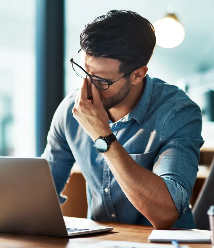 a man sitting at a desk with his hand on his face