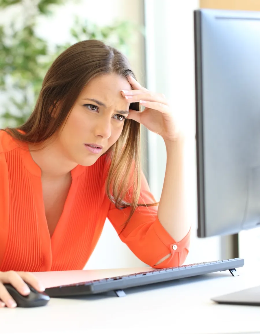 a woman sitting at a desk with a computer and a plant