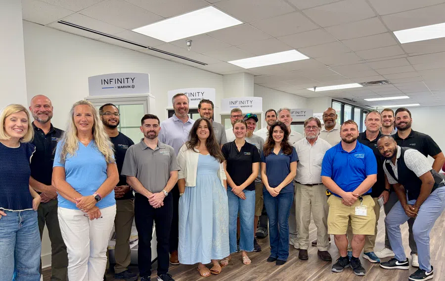 Group of diverse professionals standing together inside an office with Infinity Marvin branded displays behind them.