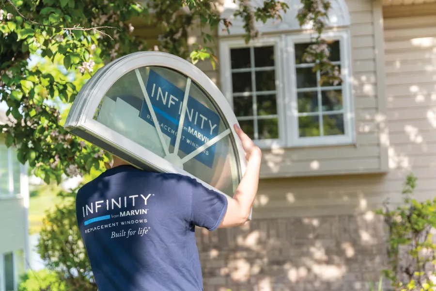 North Georgia Replacement Windows installer carrying a custom white half round window toward a customers house for installation.