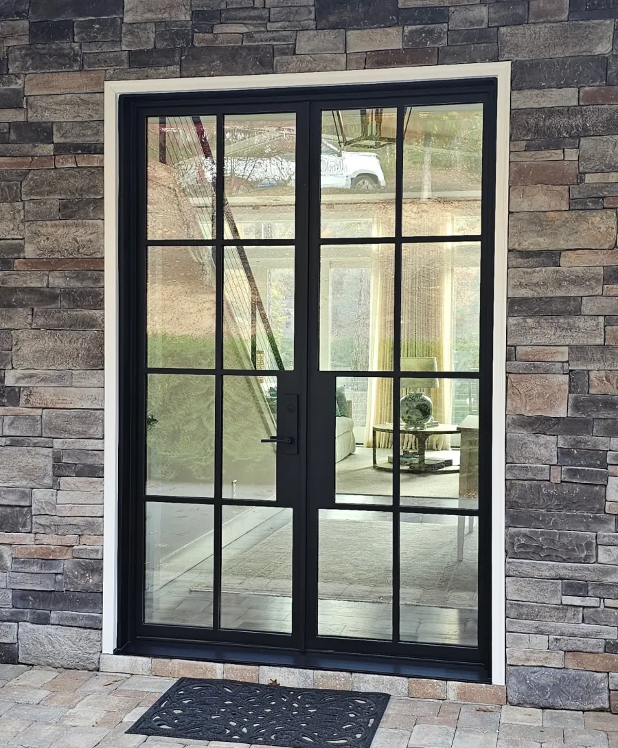 Iron entry door in a stone wall, enhancing modern home entryway.