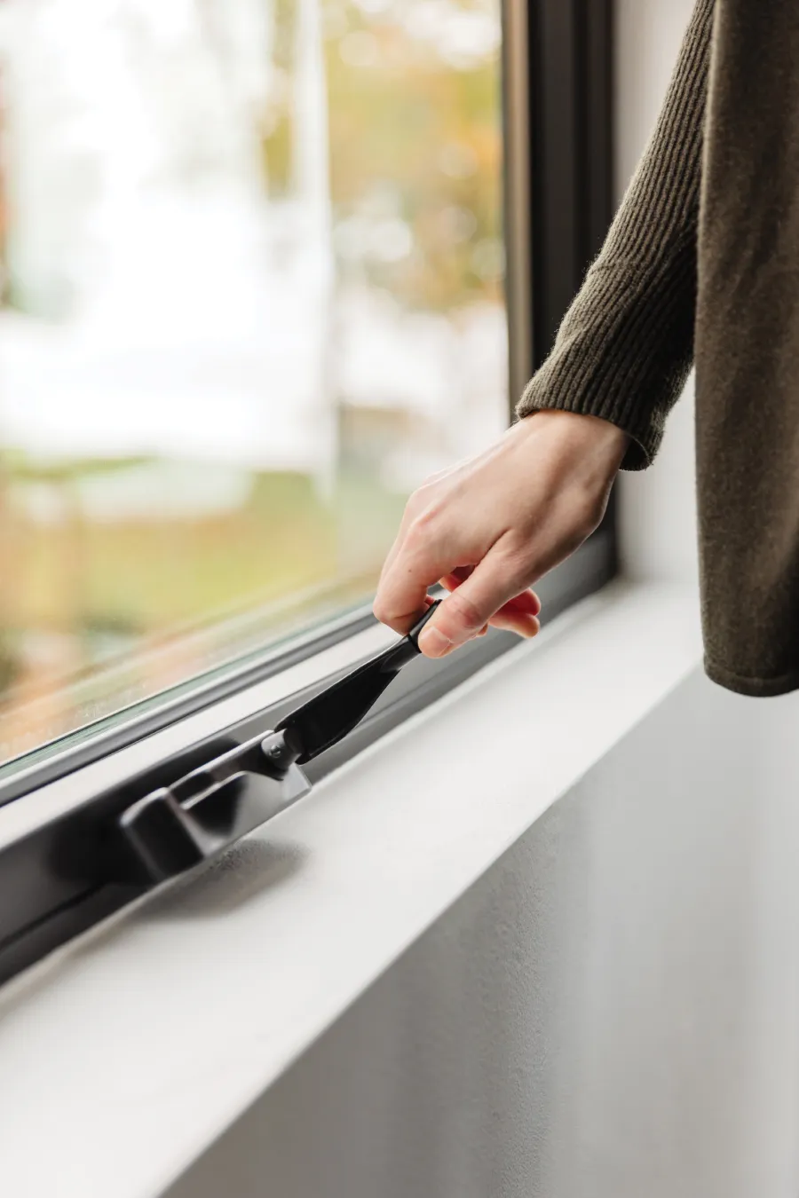 Hand crank being operated on a casement window