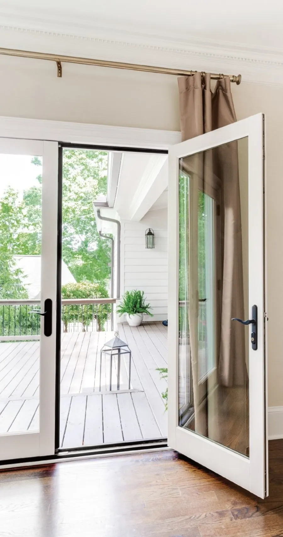 a room with a wood floor and a glass door with a plant in it