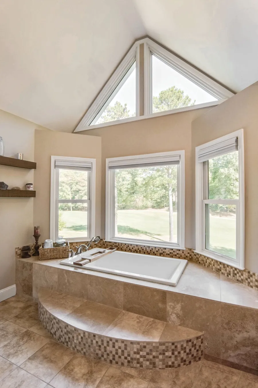 Luxurious bathroom with large bathtub, mosaic tile accents, and large windows with nature views.