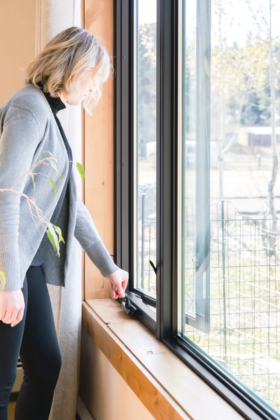 A woman opening a black casement window installed by the trusted experts at North Georgia Replacement Windows