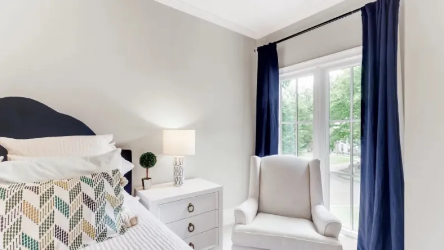 a bedroom with a bed and a chair with 2 white Infinity from Marvin casement windows