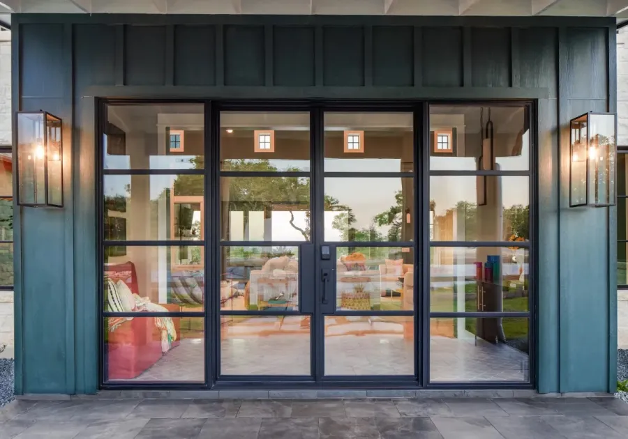 Modern black-framed glass patio doors with outdoor lantern lights and indoor living room visible through glass.