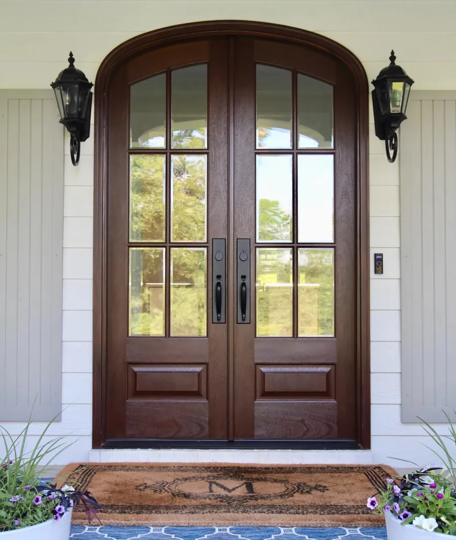 Dark brown wood stained double arched front door with glass inserts