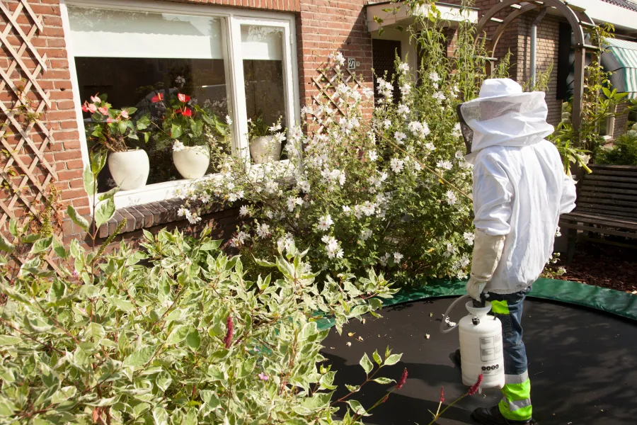 a person in a white coat watering a flower