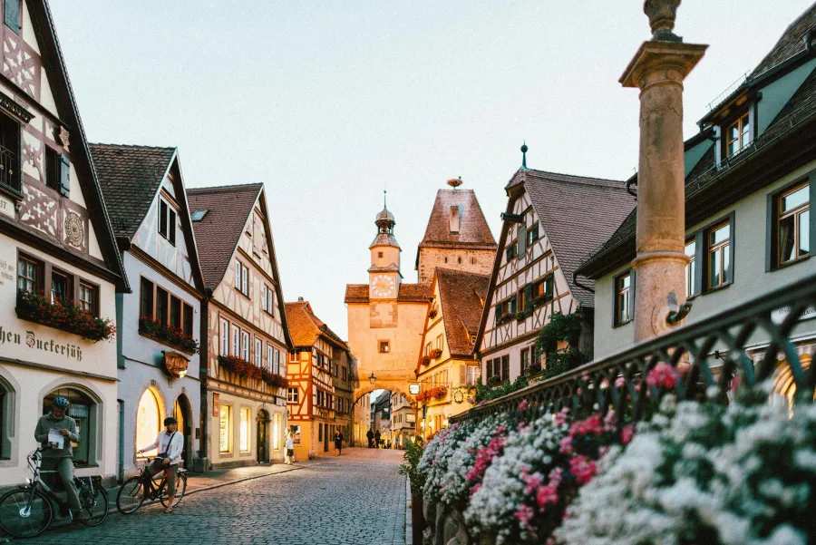 Cobblestone street in a historic European town with half-timbered houses and a medieval tower at dusk.