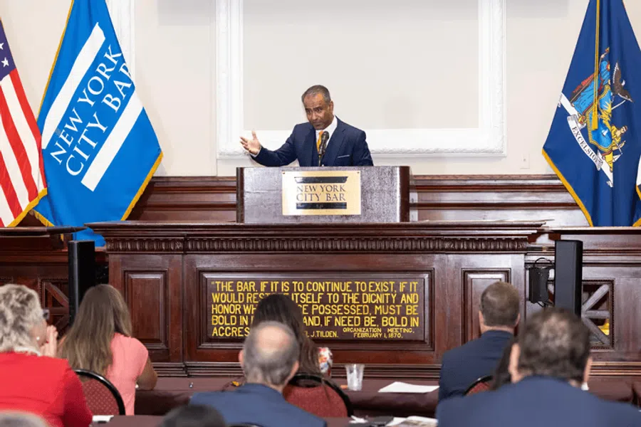 Man speaking at New York City Bar podium to an attentive seated audience in a formal event room.