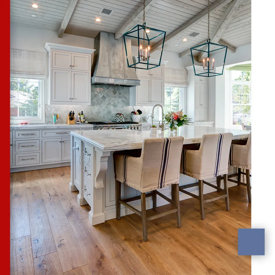 Bright modern kitchen with white cabinets, large marble island, wood flooring, and stylish pendant lighting.
