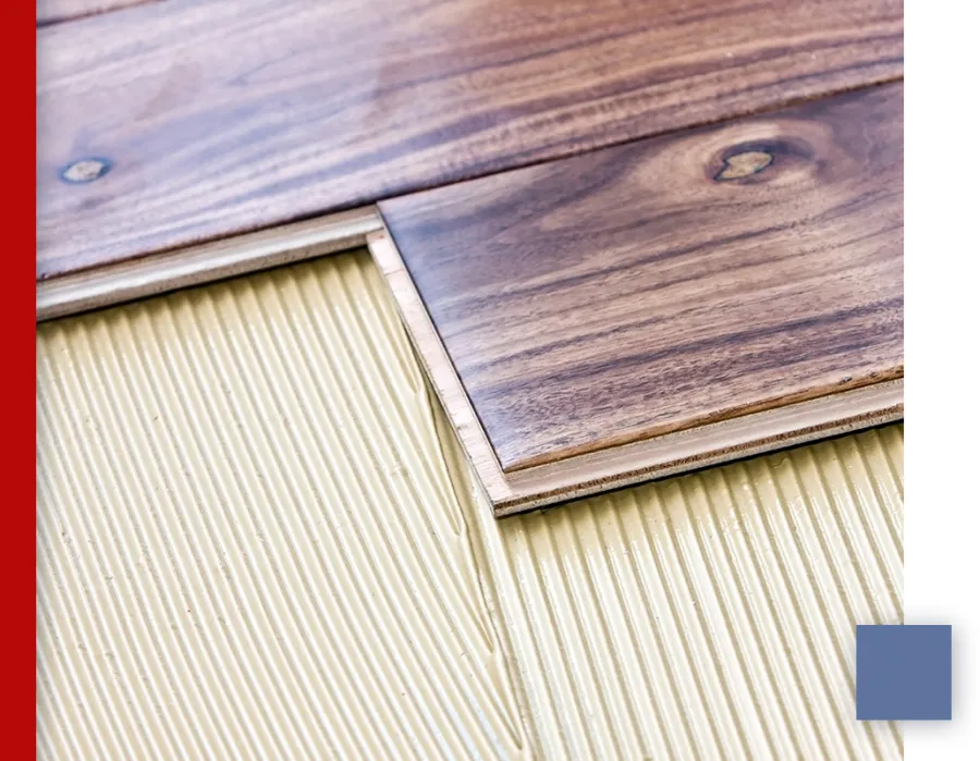Close-up of vinyl plank flooring installation showing wood grain texture and adhesive underneath.
