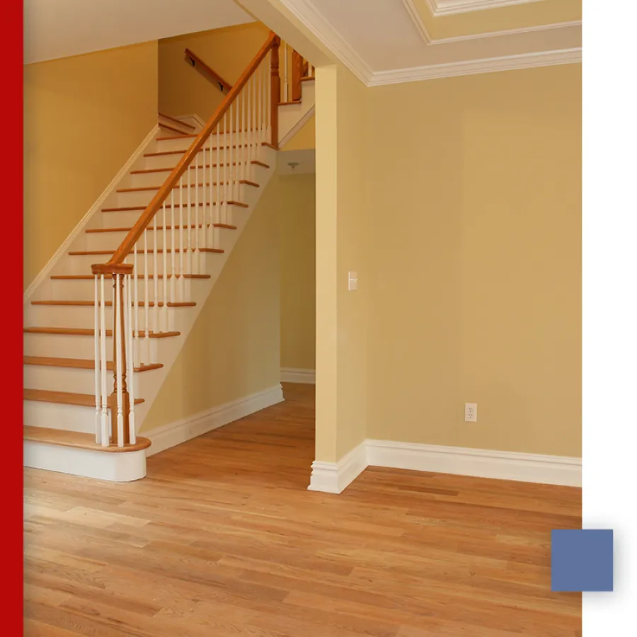 Empty room with polished natural wood flooring and white walls in bright natural light.